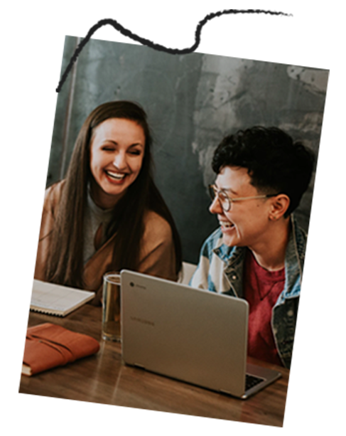 Students laughing with laptops on desk